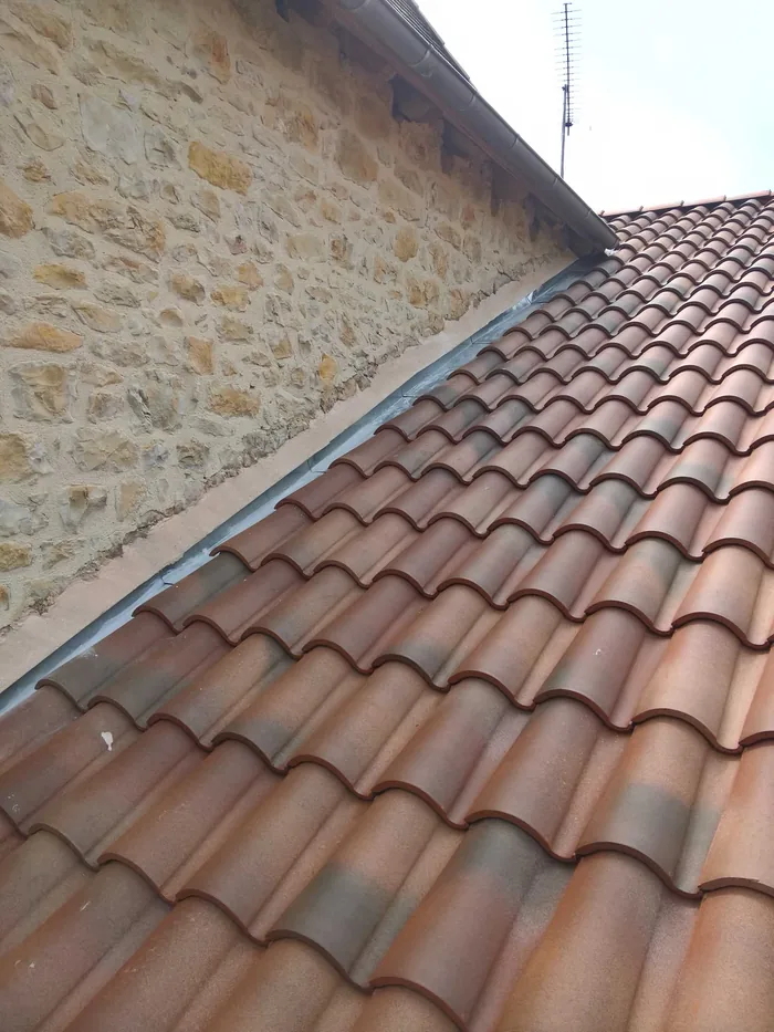 Jonction entre une toiture ancienne en pierre et une couverture neuve en tuiles