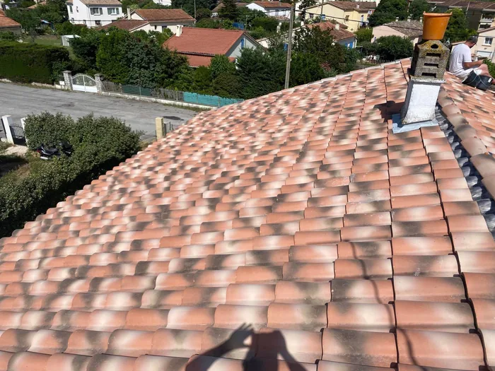Couvreur intervenant en hauteur près d’une souche de cheminée, toiture en tuiles